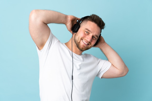 knappe man op blauwe muur luisteren muziek