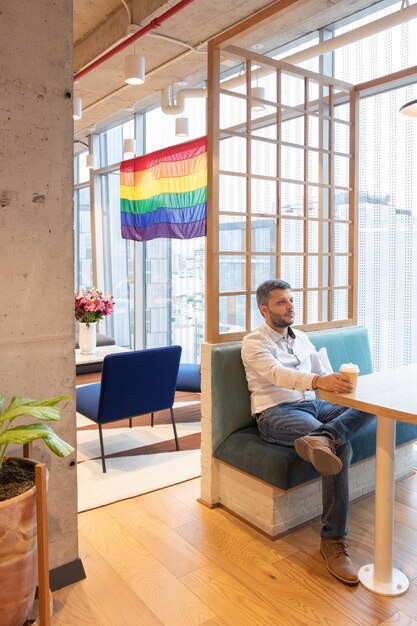 Foto knappe man overweegt de vlag die de lgbt-gemeenschap vertegenwoordigt