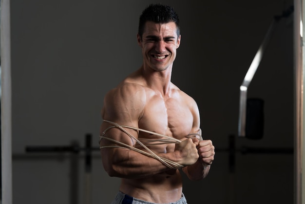 Knappe Man permanent sterk In de sportschool en buigen spieren met kabel gespierde atletische Bodybuilder Fitness Model poseren na oefeningen