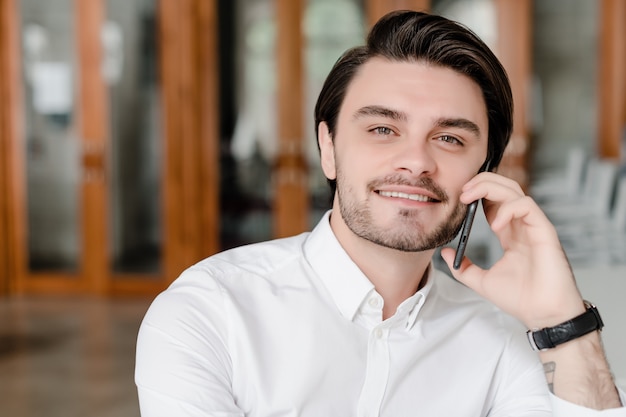 Knappe man praten aan de telefoon in het kantoor