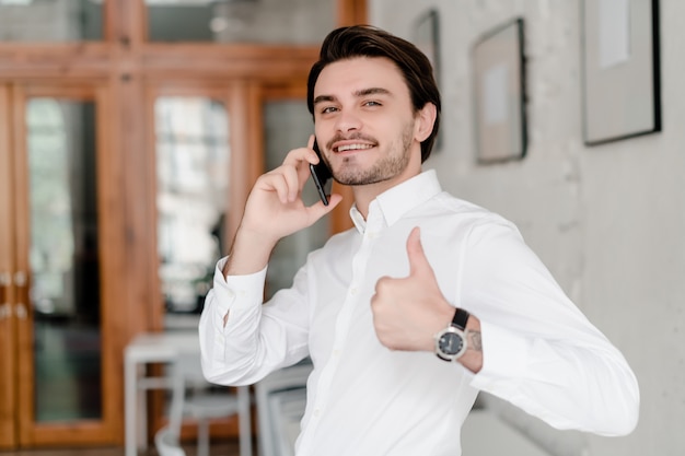 Knappe man praten aan de telefoon in het kantoor