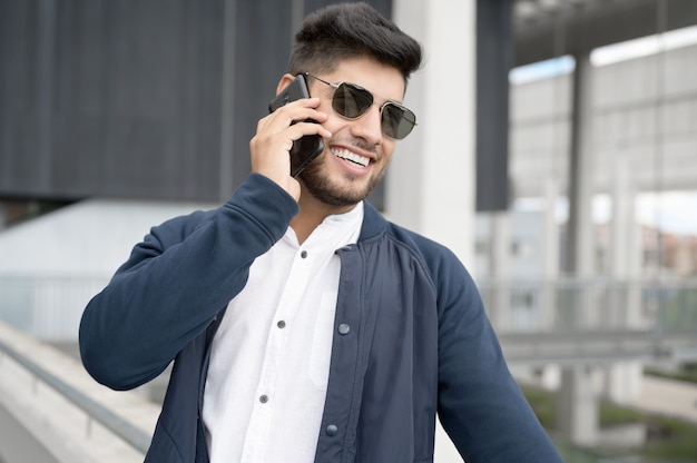 Knappe man praten op mobiele telefoon in modern kantoorgebouw