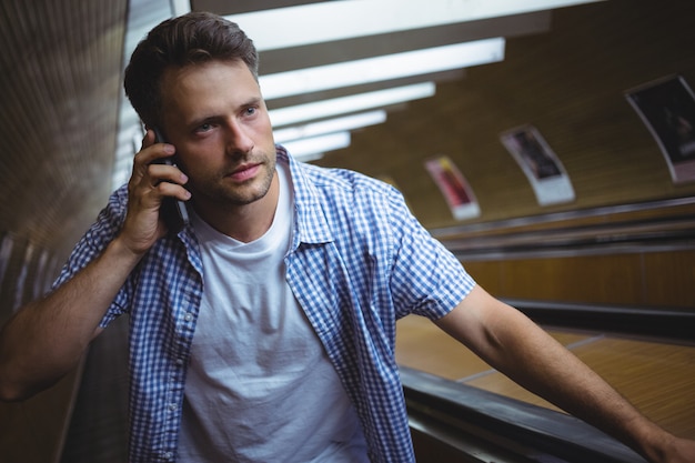Knappe man praten op mobiele telefoon op roltrap