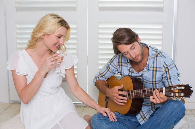 Knappe man serenading zijn vriendin met gitaar