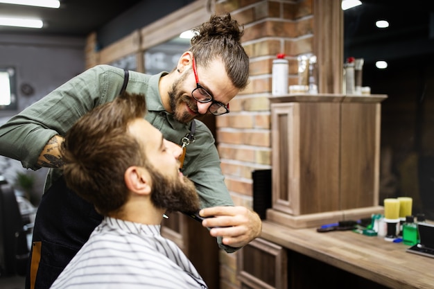 Knappe man tijdens baard- en snorverzorging in kapperszaak