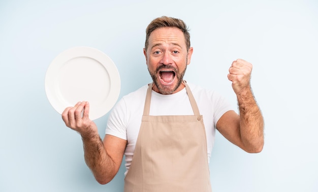 Knappe man van middelbare leeftijd die zich geschokt voelt, lacht en succes viert. leeg schotelconcept