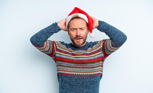 Foto knappe man van middelbare leeftijd die zich gestrest, angstig of bang voelt met de handen op het hoofd kerstconcept