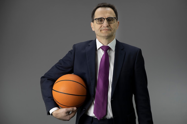 Knappe man van middelbare leeftijd in formele kleding houdt basketbal in de hand. Kopieer ruimte