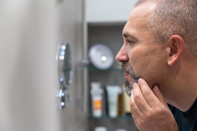 Foto knappe man van middelbare leeftijd met scheermes in badkamer