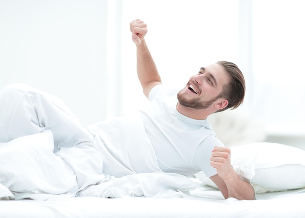 Knappe man wakker in een gezellige slaapkamerfoto met kopieerruimte