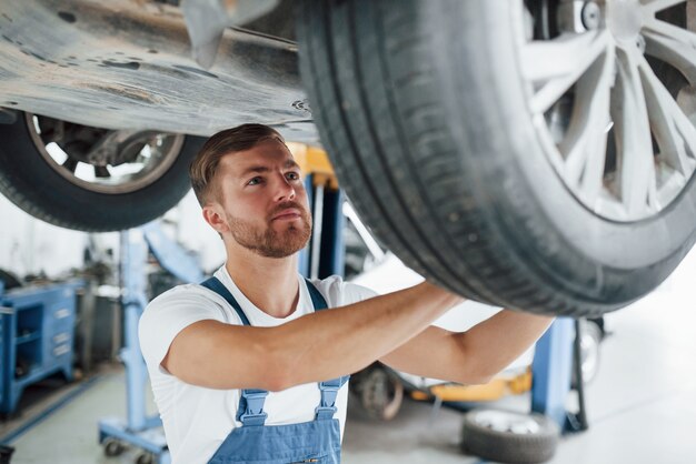 Knappe man. Werknemer in het blauw gekleurde uniform werkt in de autosalon