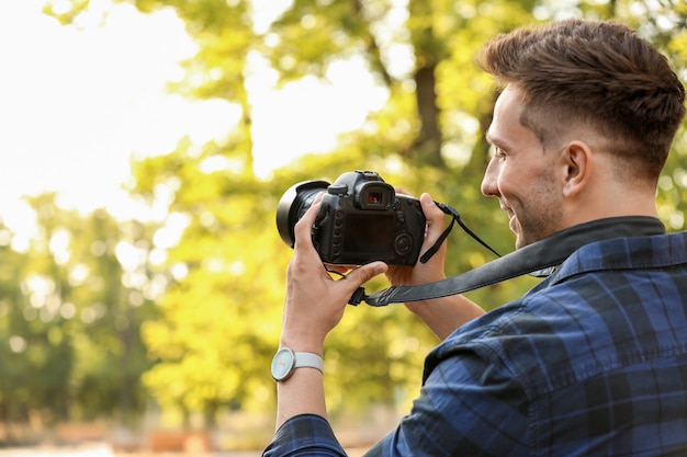 Knappe mannelijke fotograaf met camera buitenshuis