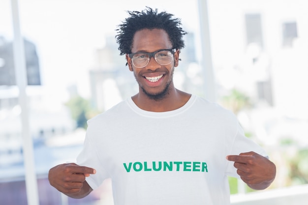 Knappe mens die aan zijn vrijwilligerst-shirt richt