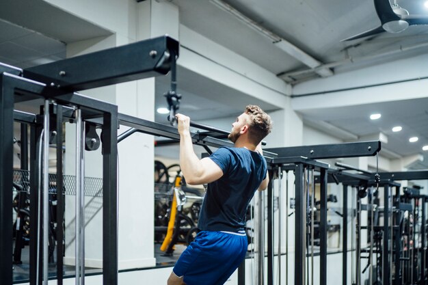 Knappe mens die bodybuilding gewichten in gymnastiek uitoefenen