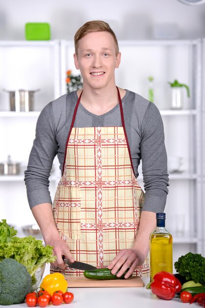 Knappe mens die thuis voorbereidend salade in keuken koken.