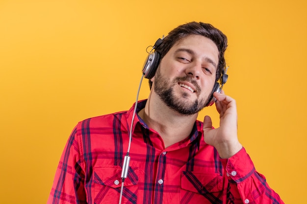 Knappe moderne man luisteren muziek in koptelefoon op geel