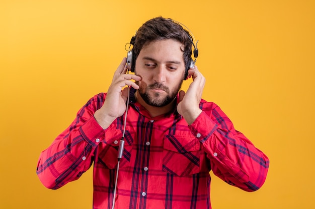 Knappe moderne man luisteren muziek in koptelefoon op geel