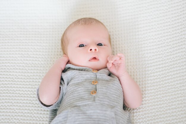 Knappe modieuze kleine jongen liggend op een deken, met een lieve uitdrukking