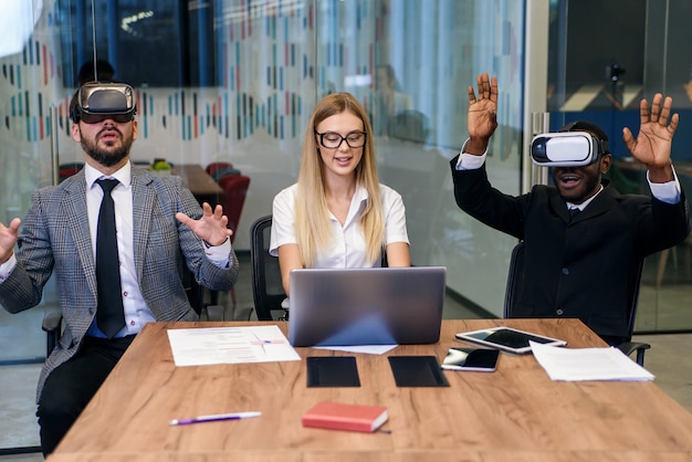 Knappe professionele gemengd ras twee mannelijke en een vrouwelijke collega's met een laptop en virtual reality-bril. Modern technologieconcept bij bedrijfsontwikkeling.