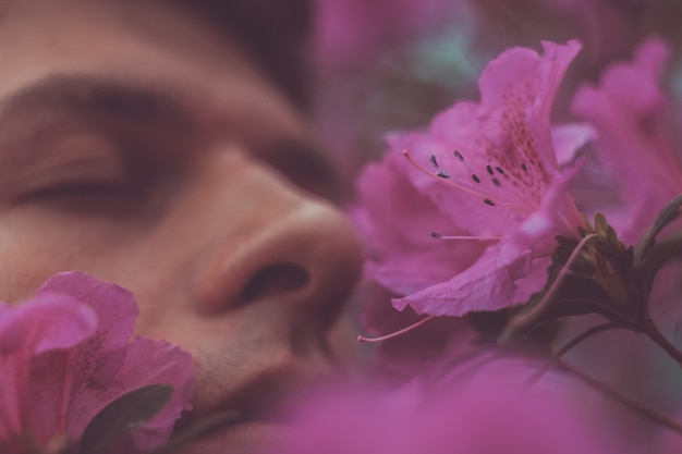 Knappe rustige man met bloemen in zijn mond. Mensen, emoties, zomer of lente concept. Lente allergie. Gezicht close-up portret.