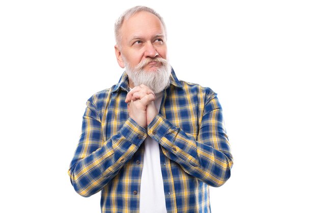 Knappe senior gepensioneerde grijsharige man met een baard in een shirt op een witte achtergrond