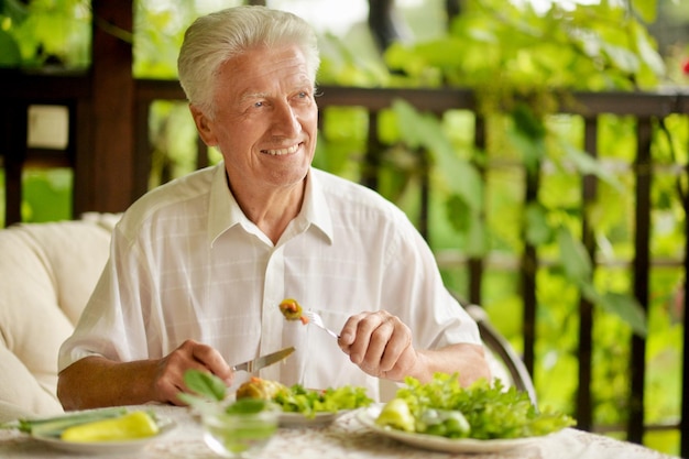 Knappe senior man die buiten een gezond ontbijt eet