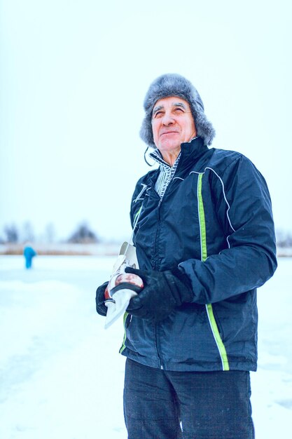 Knappe senior man in de zonnige winter natuur gaan schaatsen.