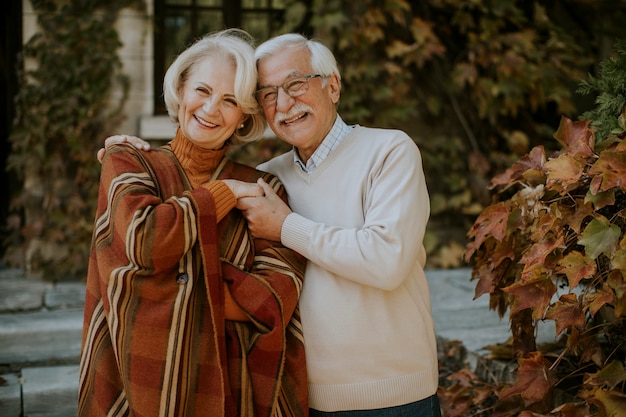 Knappe senior paar omarmen in herfst park