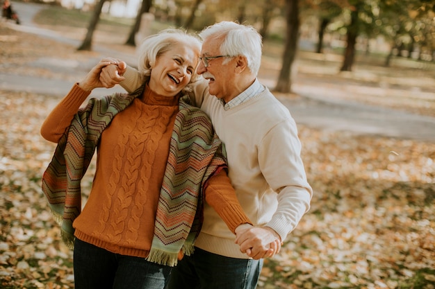 Knappe senior paar omarmen in herfst park