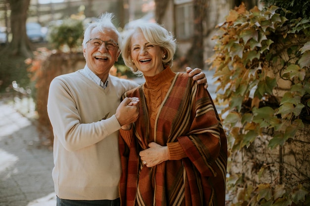 Knappe senior paar omarmen in herfst park