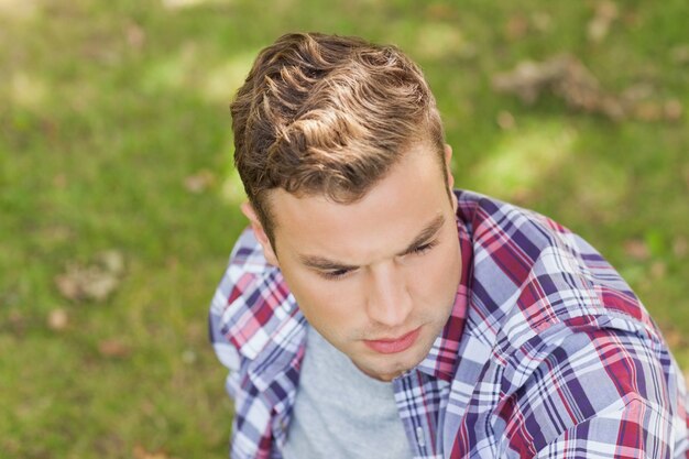 Knappe serieuze student zittend op het gras