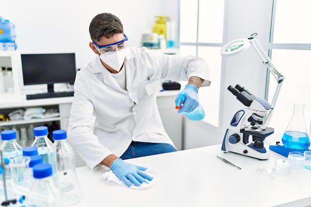 Knappe Spaanse man aan het werk als wetenschapper die de tafel schoonmaakt in het laboratorium