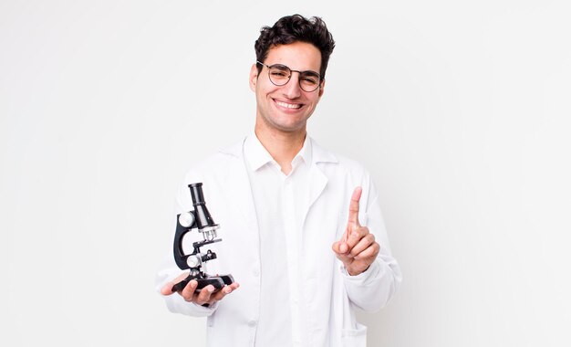 Knappe Spaanse man die trots en zelfverzekerd glimlacht en nummer één wetenschapper maakt met microscoopconcept