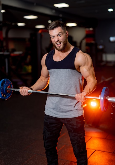 Knappe sterke atletische fitness mannen oppompen van armspieren met barbell. Gespierde bodybuilder mannen doen bodybuilding biceps oefeningen in de sportschool.