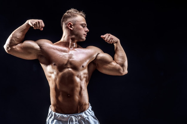 Knappe sterke bodybuilder poseren in studio op zwart