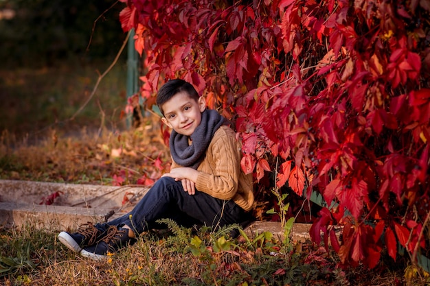 Knappe stijlvolle jongen die in herfstparkstijlmode staat