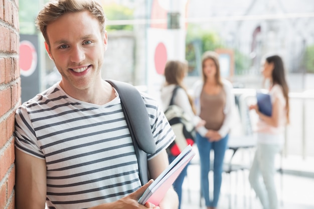 Knappe student die en blocnotes glimlacht houdt