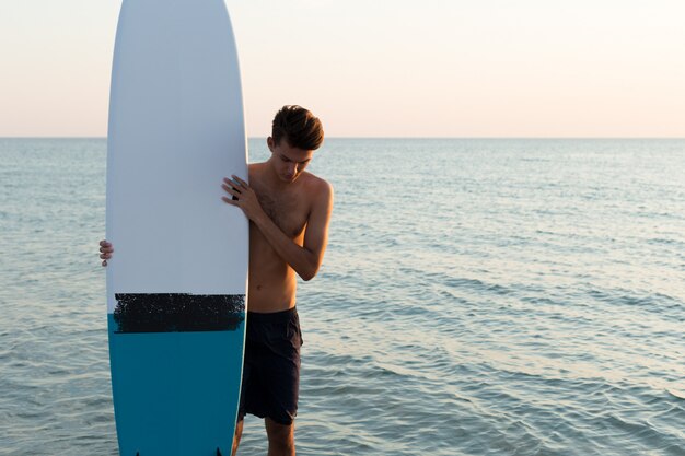 Knappe surfer die zijn surfplank houdt