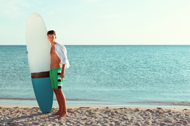 Knappe surfer die zijn surfplank houdt