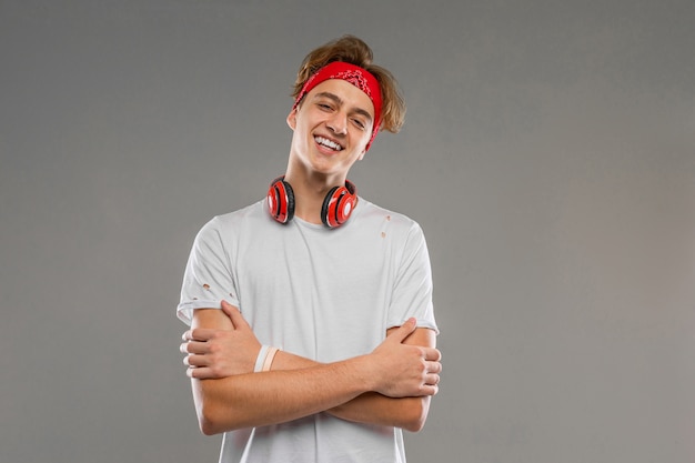 Knappe tiener met koptelefoon, jonge man in een lichte t-shirt tegen een grijze muur achtergrond