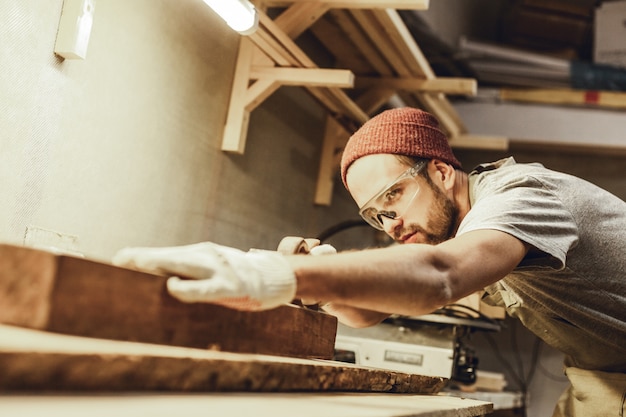 Knappe vakman die met plank werkt