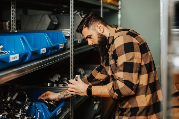 Knappe volwassen man aan het werk in het magazijn voor reserveonderdelen voor auto's en vrachtwagens.