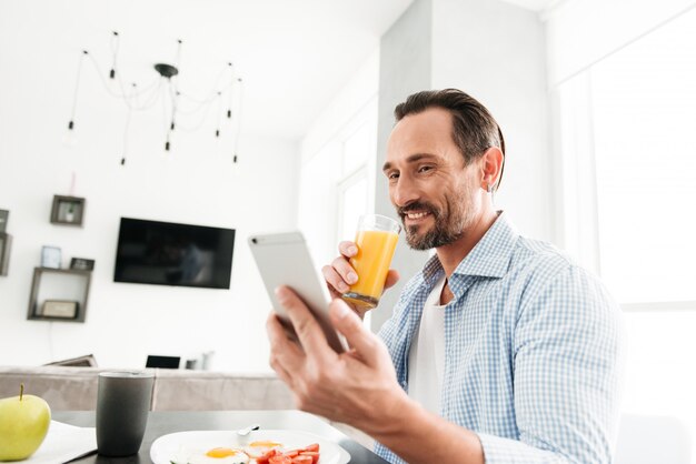 Knappe volwassen man met behulp van mobiele telefoon