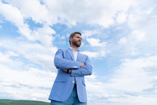 Knappe volwassen man zakenman in formeel pak check tijd op polshorloge op hemelachtergrond charisma