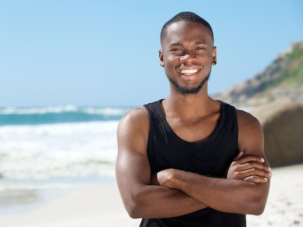 Knappe vrolijke man die lacht op het strand