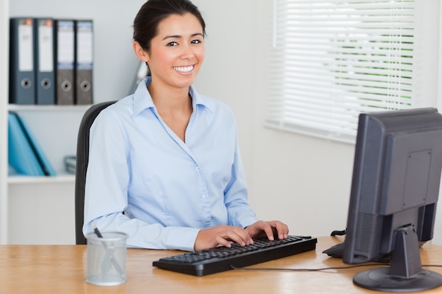 Knappe vrouw die aan een computer werkt terwijl het zitten