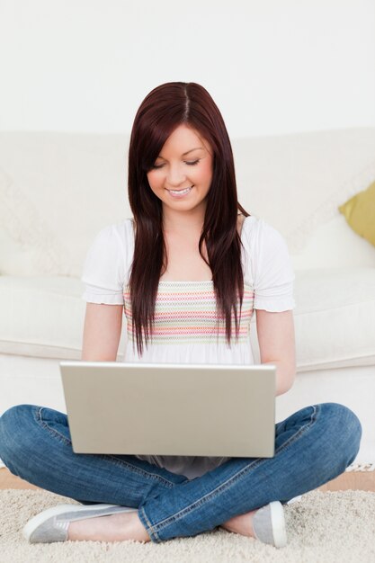 Knappe vrouw die met haar laptop ontspannen terwijl het situeren op een tapijt