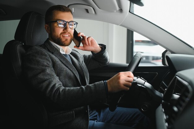 Knappe zakenman die met de auto naar de luchthaven rijdt en op zakelijke zijaanzicht kopieert