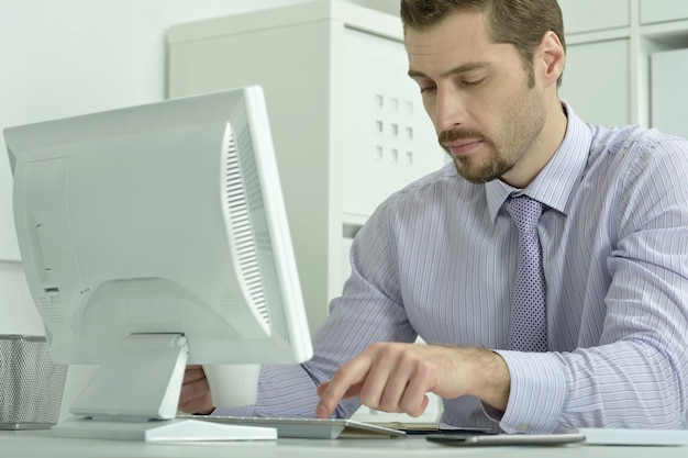 Knappe zakenman die met laptop op kantoor werkt