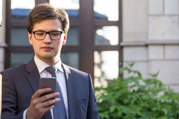 Knappe zakenman die mobiele telefoon met behulp van